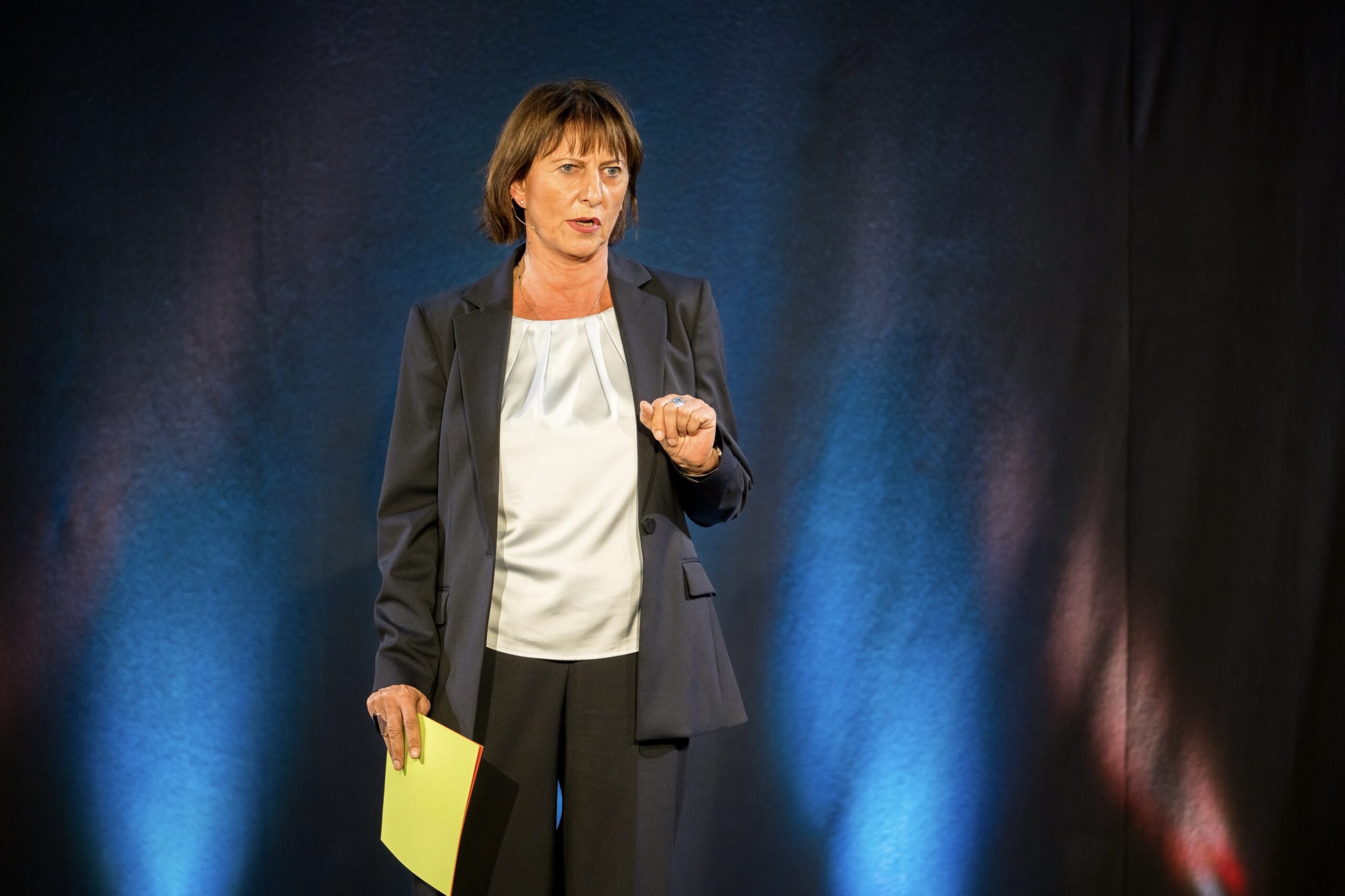 Dr. Claudia Neumann steht auf der Bühne und hält einen Vortrag.