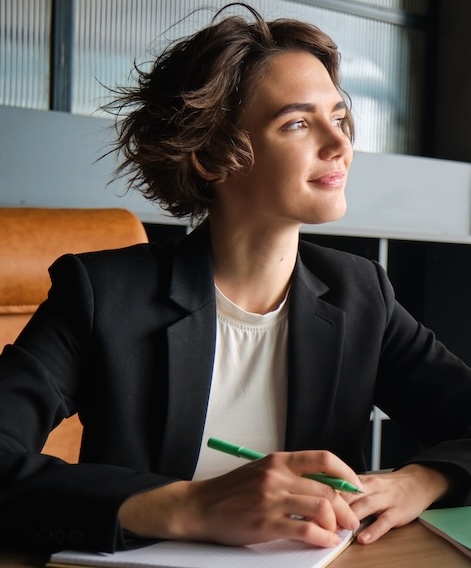 Junge Frau zufrieden und entspannt am Schreibtisch auf der Arbeit. Work Life Balance stimmt.
